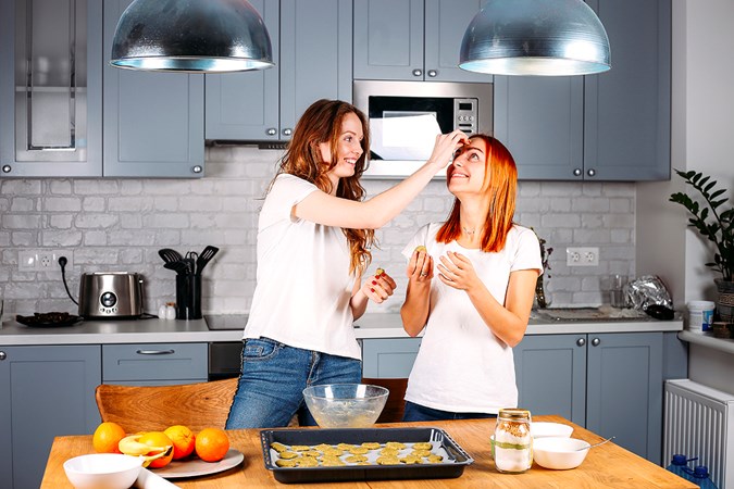 Två yngre kvinnor som bakar i ett kök.